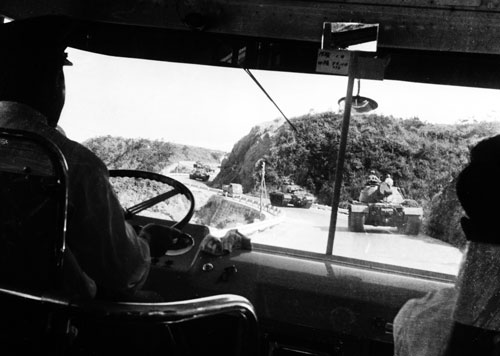 沖縄は今も昔も「戦場の島」。幹線道路を走行する米軍戦車の列。政府は「日米地位協定に定めた施設間移動」として、「復帰」後も住民の抗議を聞きいれない。＝1960年、路線バスの中から、恩納村