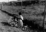 米軍基地のフェンスにさえぎられ、いまも墓参りさえままならない老女たち。彼女らの前に立ちはだかるのは、なにを隠そう、沖縄への差別政策を改めようとしない「日本の壁」だ。1987年、沖縄県那覇市