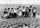 初めて訪ねた伊是名島の浜辺で出会った腕白少年たち。この日、僕は靴も靴下も脱ぎすてて彼らと浜遊びに興じた。1960年