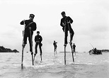 １キロ先の親島まで竹馬で海を渡って通学する子どもたち。冬の冷たい海風を全身に受けながら、広い海の上を30分かけて歩いていた。1966年、沖縄・久米島